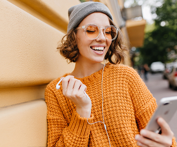 A smiling girl in a brown sweater looks at her phone